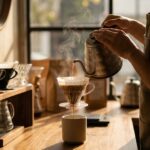 Barista prepares a pour-over coffee at Once Café, pouring hot water through a dripper as steam rises in the warm light of the morning.